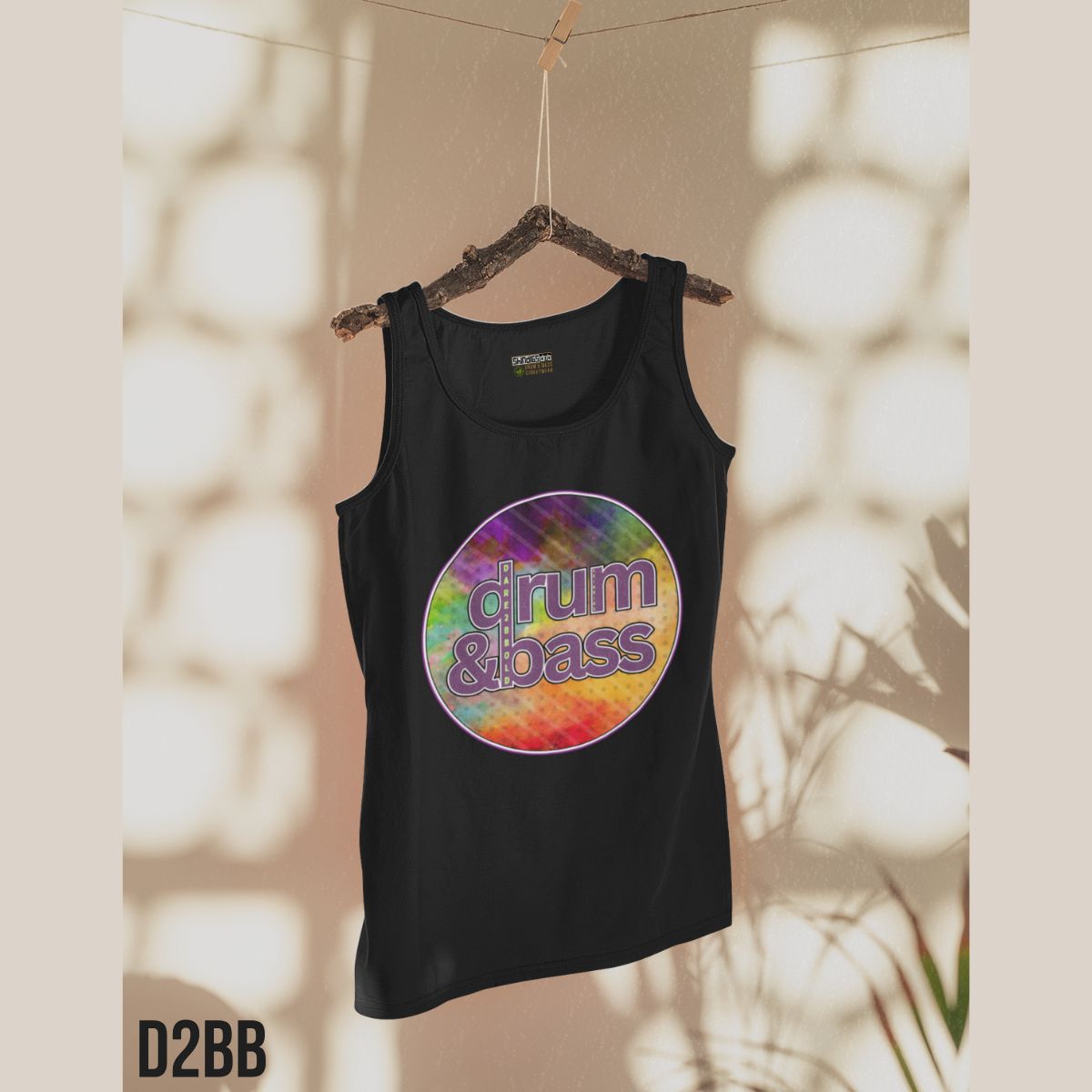 Black tank top with colorful 'drum & bass' design on a hanger against a neutral background