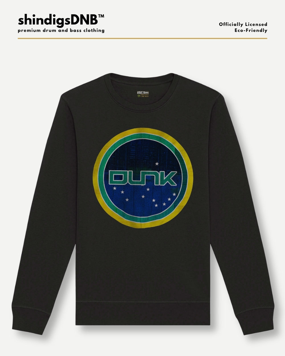 A black crewneck sweatshirt featuring a circular graphic on the chest with the word 'DUNK' in green, surrounded by blue, green, and yellow rings with small white stars. The brand 'shindigsDNB' is displayed at the top left with 'Officially Licensed Eco-friendly' at the top right.