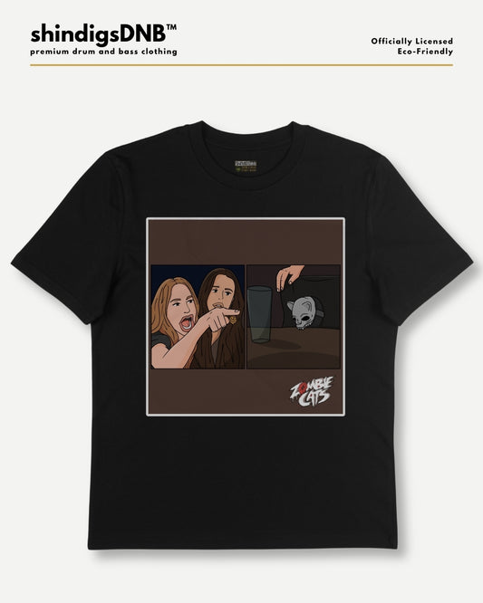 A black short-sleeve t-shirt with a square graphic print on the front, featuring an illustration of two women and a zombie, with the text 'Zombie Girls' in a stylized font. The shirt is displayed flat against a light gray background with branding text for 'shindigsDNB' at the top.