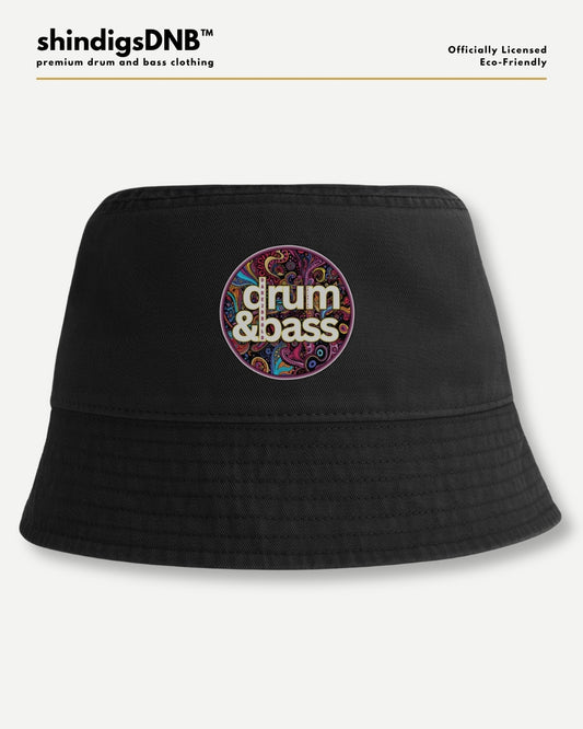 A black bucket hat with a colorful circular graphic on the front that reads 'drum & bass' in white text over a psychedelic pattern. The hat is displayed on a light gray background with 'shindigsDNB' branding at the top.